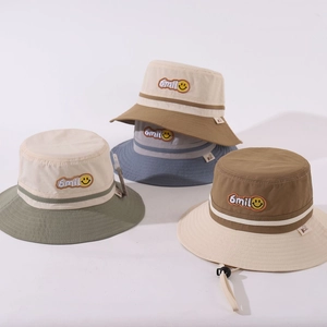 Detail of color-block kids bucket hats with embroidered smile face and windproof strap