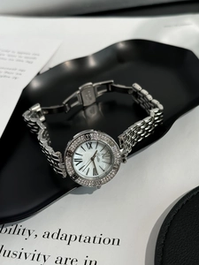 Detail view of a silver women's watch with crystal bezel and Roman numeral dial on a black tray