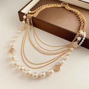 Detail of multi-layer gold necklace with white pearls and sparkling floral pendants