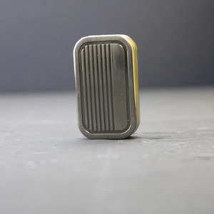 Detailed macro view of the silver metal EDC haptic coin with vertical stripe textures