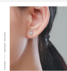 Close-up of minimalist S925 sterling silver drop earring with tiny gems on model