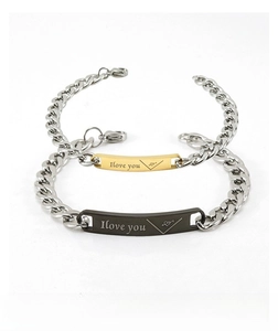 Détail de bracelets de couple avec chaîne argentée et plaques gravées en or et noir