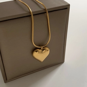 Minimalist gold heart pendant necklace with smooth square snake chain on jewelry box