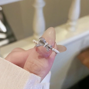 Elegant silver open ring with zircon bow design and small white pearls on finger