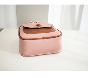 Detail of a pink and brown crossbody bag featuring a golden metal bow and snap closure