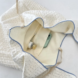 Vue intérieure du sac en toile gaufrée blanche à pois avec liseré bleu et poche zippée