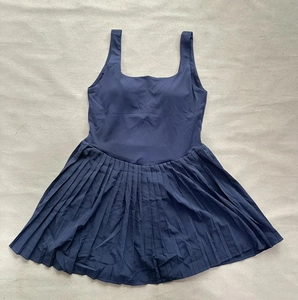 Detailed flat lay of navy blue pleated tennis dress showing U-neck and elastic fabric