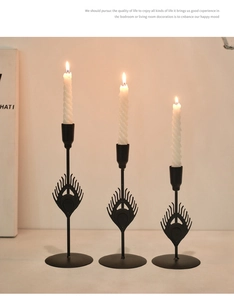 Detail view of black metal peacock feather candlesticks with white spiral candles