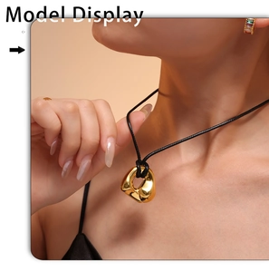 Detail of a minimalist gold curved organic pendant on a black adjustable cord necklace