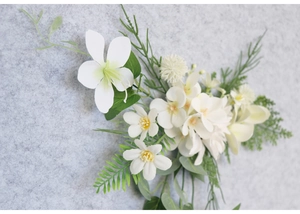 Close-up of elegant bridal hair clip with white silk flowers and green foliage
