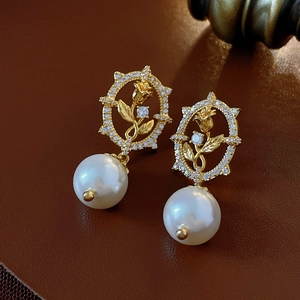 Detailed close-up of vintage gold rose earrings with white pearls and diamonds