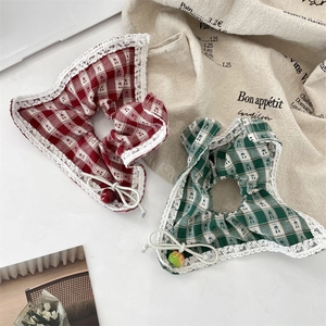 Detail of red and green plaid scrunchies with white lace edges and cherry fruit charms
