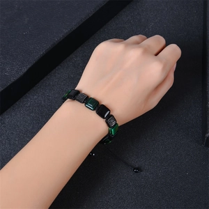 Macro shot of square malachite and obsidian beads on a black woven adjustable bracelet