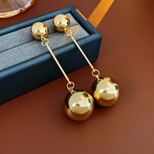 Detail view of long gold metallic double sphere tassel earrings on blue velvet box