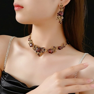 Close-up of vintage gold necklace and earrings set with deep red gems on a model