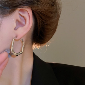 Close-up of irregular twisted silver earrings on a model showing polished metallic texture