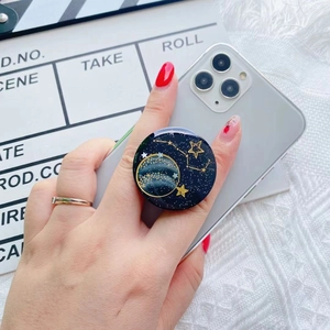 Detail of high-gloss resin phone grip featuring golden galaxy and planet motifs on black