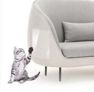 Detailed close-up of transparent self-adhesive PVC cat scratch protector on a grey sofa