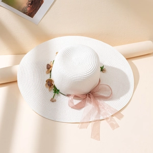 Close-up of white sun hat featuring pink floral crown and elegant organza ribbon tie