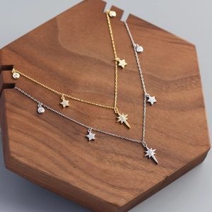 Close-up of gold and silver S925 star necklaces with cubic zirconia on wooden tray