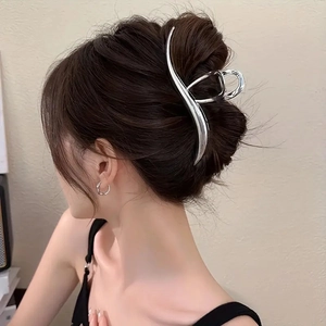 Grande pince à cheveux argentée en métal ondulé portée par un mannequin chic