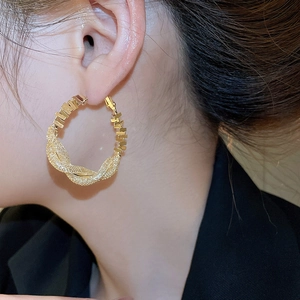 Close-up of model wearing gold-plated hoop earrings with twisted rope texture design