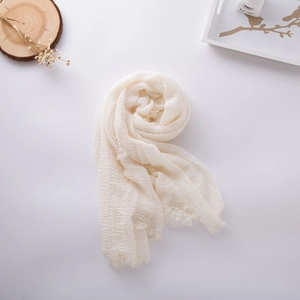 Close-up of beige cotton linen scarf featuring natural crinkle texture and frayed fringe edges