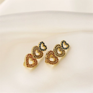 Detail view of heart-shaped gold earrings with colorful rhinestones on silk fabric