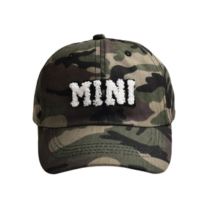 Detailed view of white chenille embroidered MINI text on camouflage baseball cap surface