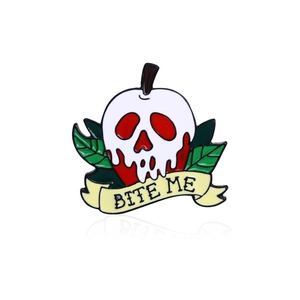 Macro detail of enamel poison apple brooch with skull face and Bite Me ribbon design