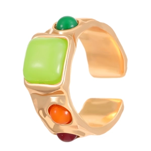 Detalle de anillo ajustable dorado con gema verde cuadrada y textura de metal martillado