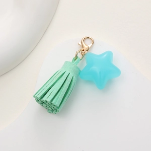 Detail of light blue translucent star keychain with green tassel and gold lobster clasp