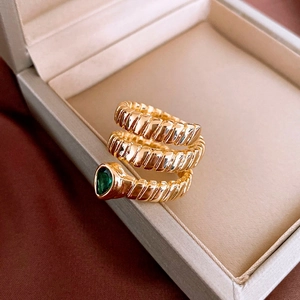 Macro detail of gold plated triple spiral snake ring with green pear cut gemstone