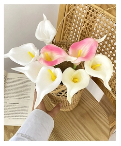 Close-up of realistic white and pink PU calla lily bouquet held over a woven basket