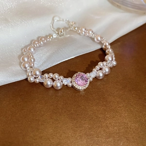 Detail of multi-row pearl bracelet with a large pink gemstone center and silver metal clasp