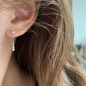 Detail of minimalist silver waterdrop earrings with dangling zircons on ear