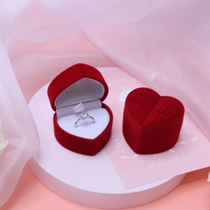 Detailed view of red heart-shaped velvet ring box with single diamond ring on soft background