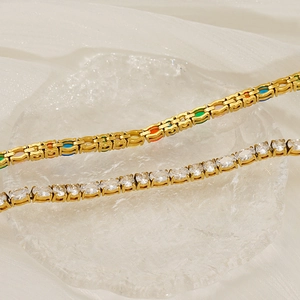 Close-up of golden tennis bracelets with colorful rectangular and oval stones on glass