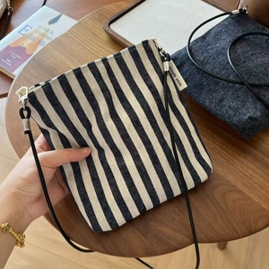 Detail of striped canvas and denim crossbody bags with metal hooks and slim straps