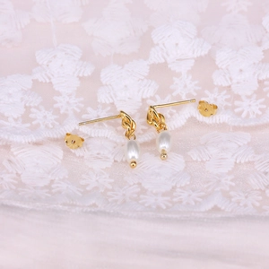 Close-up of S925 sterling silver gold plated earrings with white teardrop pearls on lace