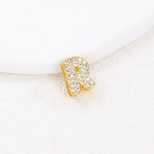 Macro shot of gold letter R pendant paved with sparkling clear cubic zirconia stones