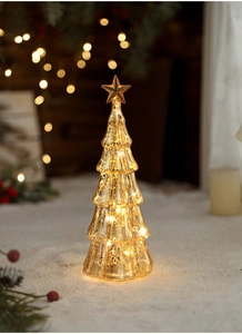 Close-up of golden light-up Christmas tree with star topper on artificial snow