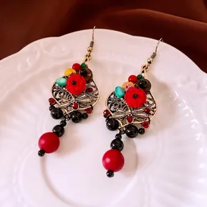 Ethnic retro dragonfly drop earrings with red petals and colorful beads on white plate