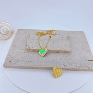 Detail of gold heart pendant with green and white yin yang pattern and O-chain