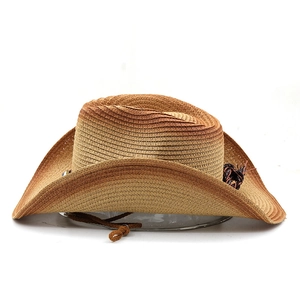 Macro detail of hand-woven straw cowboy hat showing texture and brown tassel trim