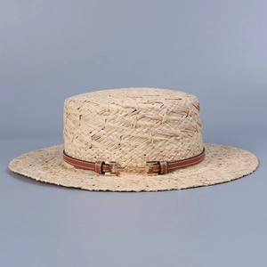 Detail of hand-woven raffia hat featuring a brown leather strap and gold metal buckle