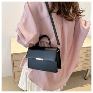Détail du sac élégant en cuir noir mat avec fermoir doré et fine bandoulière réglable