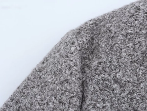 Gros plan du tissu polaire sherpa gris montrant la texture bouclée et la matière douce