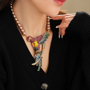 Detail of a luxury parrot pendant necklace with pearls and colorful crystals on a model