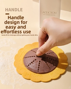 Close-up view of a sunflower-shaped silicone drain cover being lifted by its handle
